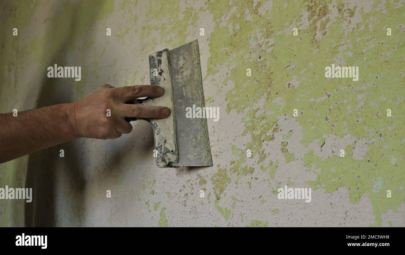 scraping off unevenness and residues of paint and plaster with a spatula, cleaning and preparing