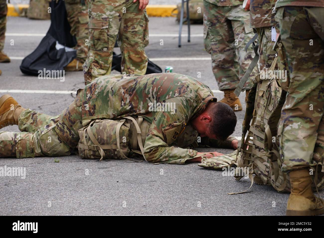 A Soldier collapses in exhaustion over his ruck sack after crossing the ...