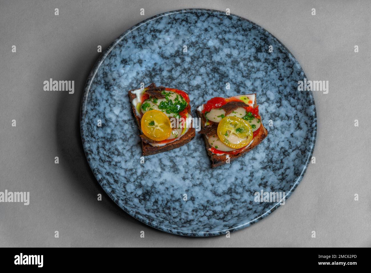 A Birdseye view of a modern plated meal, shot against a plain grey background. Stock Photo
