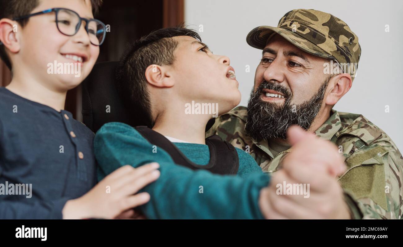 Military soldier having tender moment together his son with disability at home - Family love concept Stock Photo