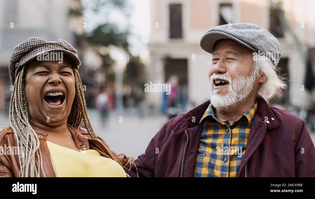 Happy multiracial senior couple having fun in city - Elderly people and love relationship concept Stock Photo