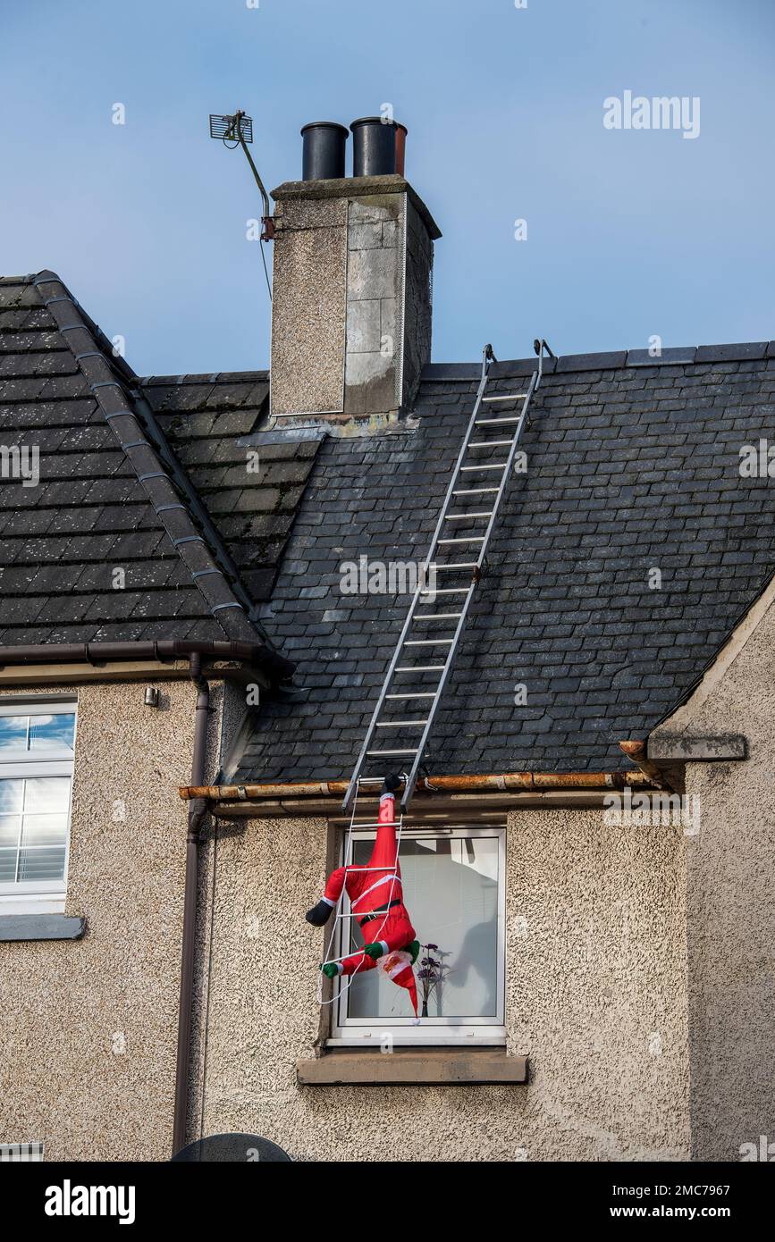 Santa Calause falling off laddders on house rooftop on Christmas Day. Stock Photo