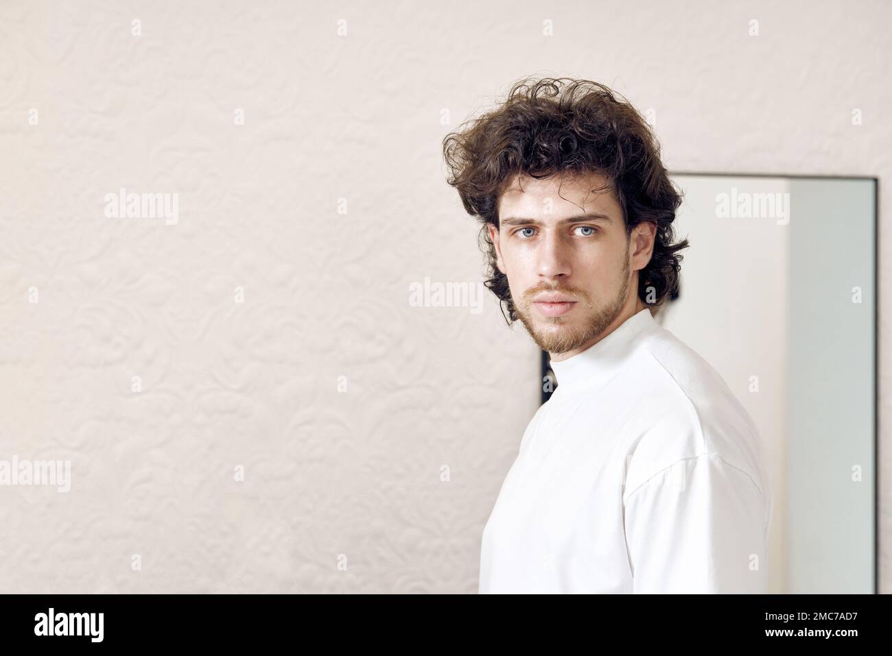 Young handsome man with curly hair in white t-shirt Stock Photo