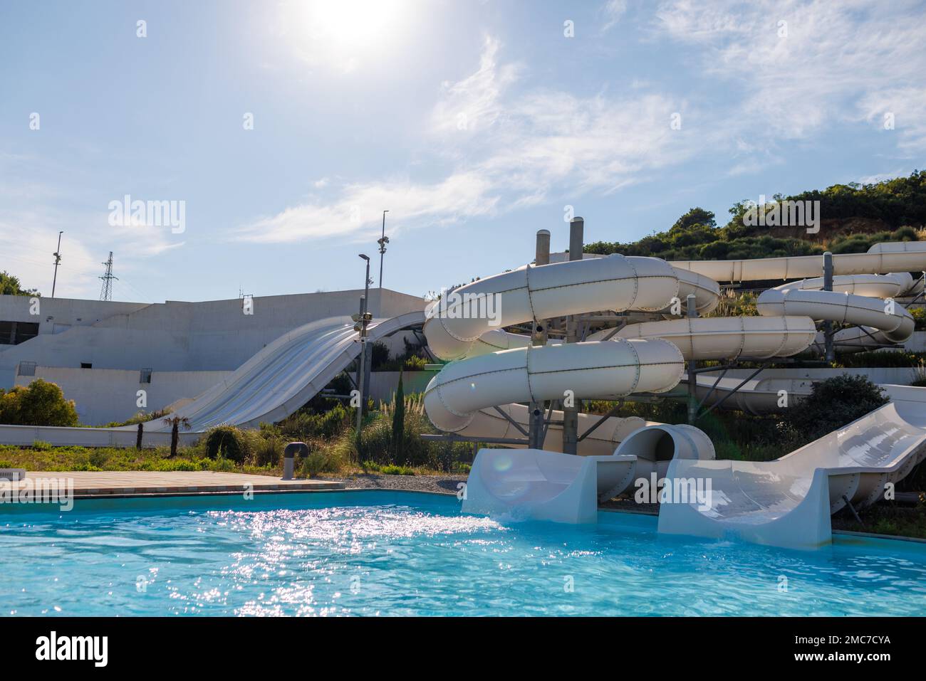 Empty water park with high white slides, pools and white sun loungers Stock Photo