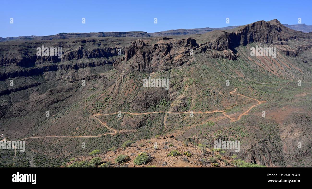 Mountains and valley with dirt road going through Bartolomé de Tirajana valley Gran Canaria Stock Photo