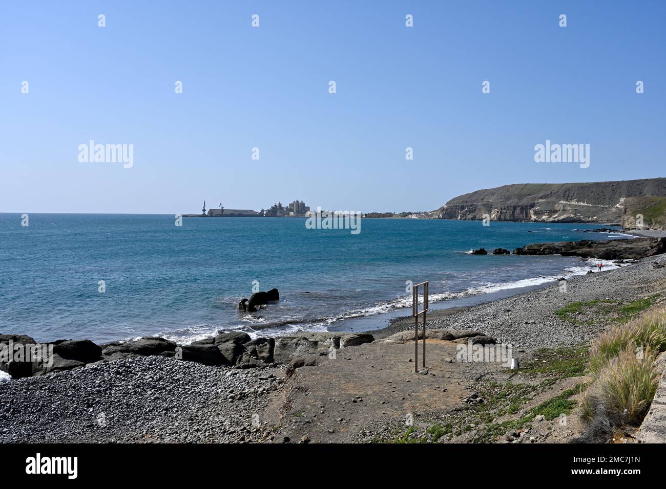 Playa de Triana pebble beach looking toward cement works in Peninsula with El Pajar which locals want to keep and central government want to convert t Stock Photo