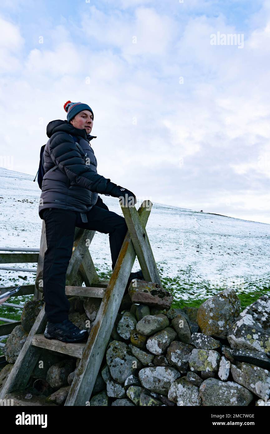 A man standing on a style in winter in the cheviot hills, Northumberland, UK Stock Photo