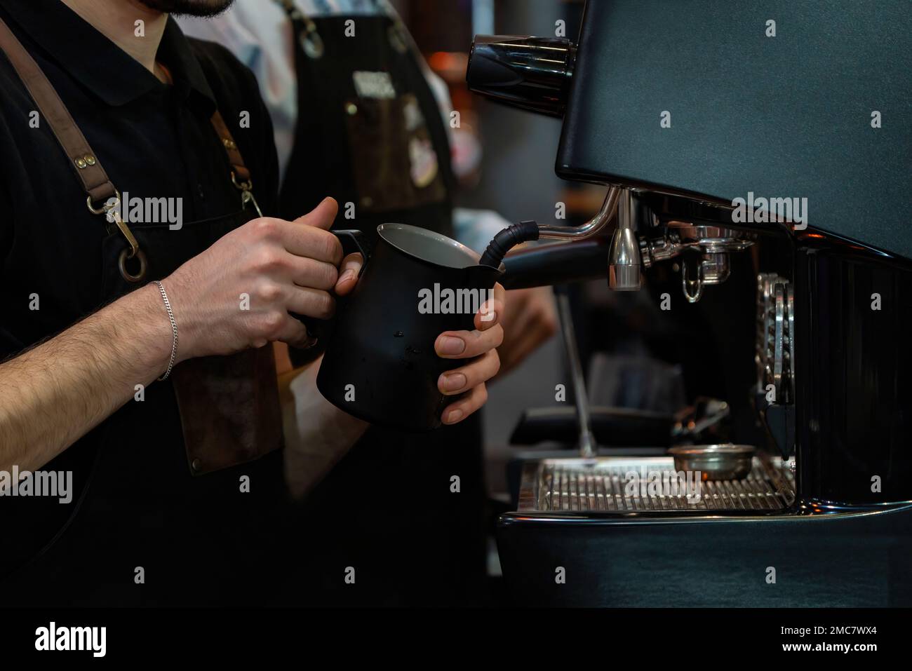 Barista frothing milk to make coffee. Barista hands in front of coffee