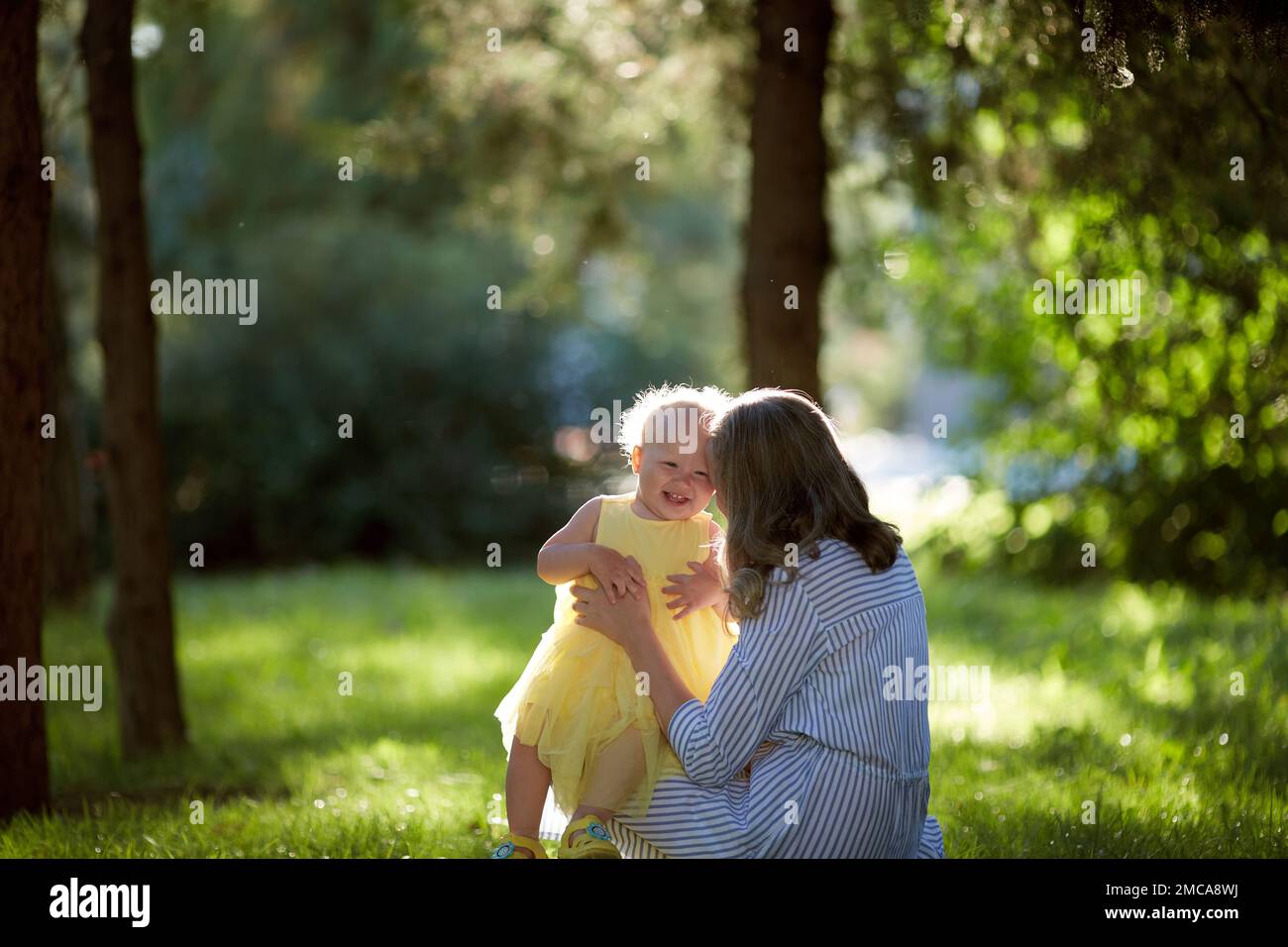 Single-parent family mother and daughter happily walk in the park on a summer day. Stock Photo