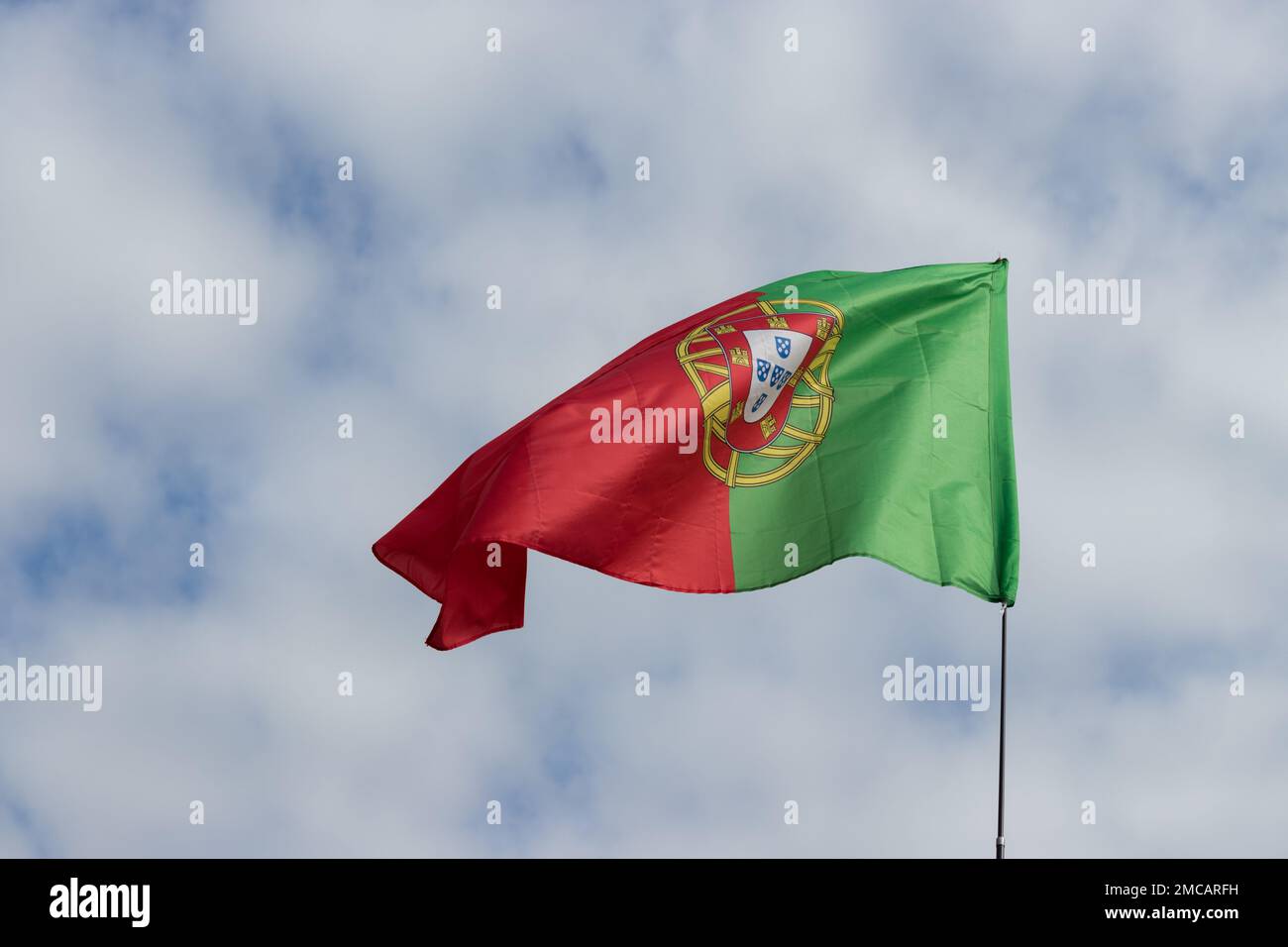 The developing Portuguese flag against the blue sky. Flag close-up in clear weather. space for text. Stock Photo