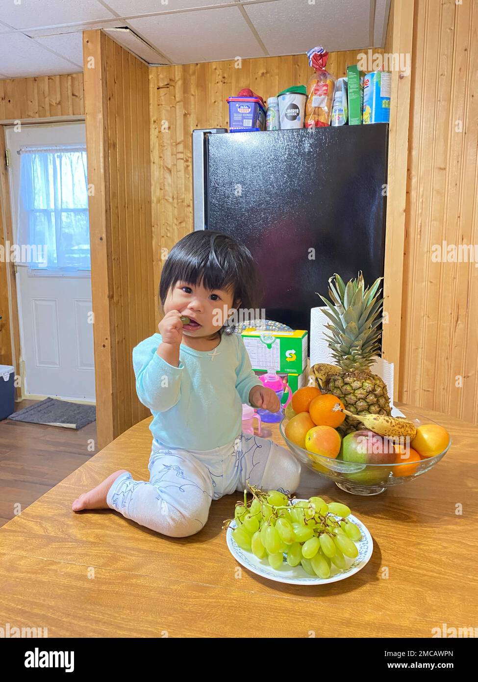 An Asian kid eating fruits on a table Stock Photo