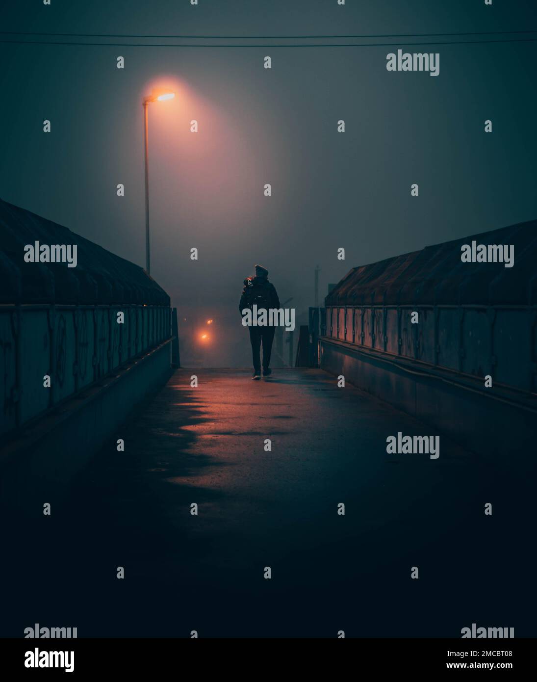 A man walking on a bridge on a foggy night Stock Photo - Alamy