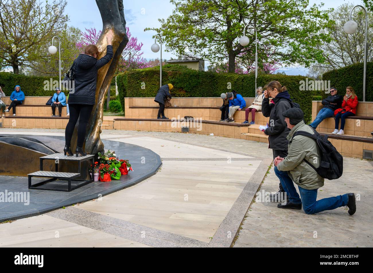 People venerating the statue of the Risen Christ in Medjugorje. The statue miraculously weeps drops of fluid from Jesus' right knee. Stock Photo