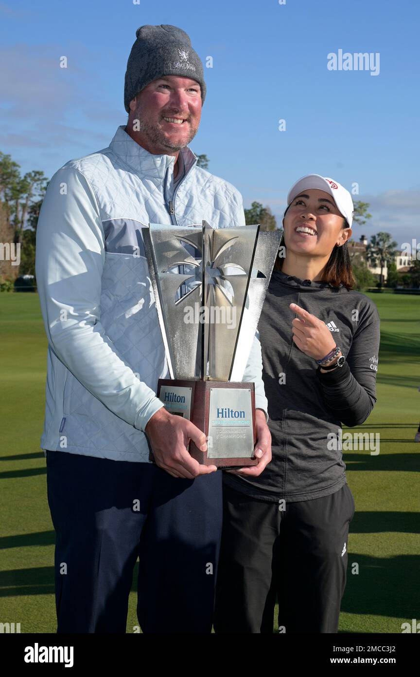 Danielle Kang, center, poses next to the championship trophy with former  professional pitcher Derek Lowe, left, after winning the Tournament of  Champions LPGA golf tournament, Sunday, Jan. 23, 2022, in Orlando, Fla. (