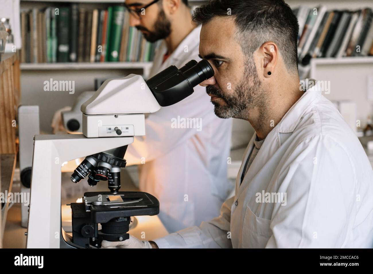 Scientist viewing sample through microscope during experiment in
