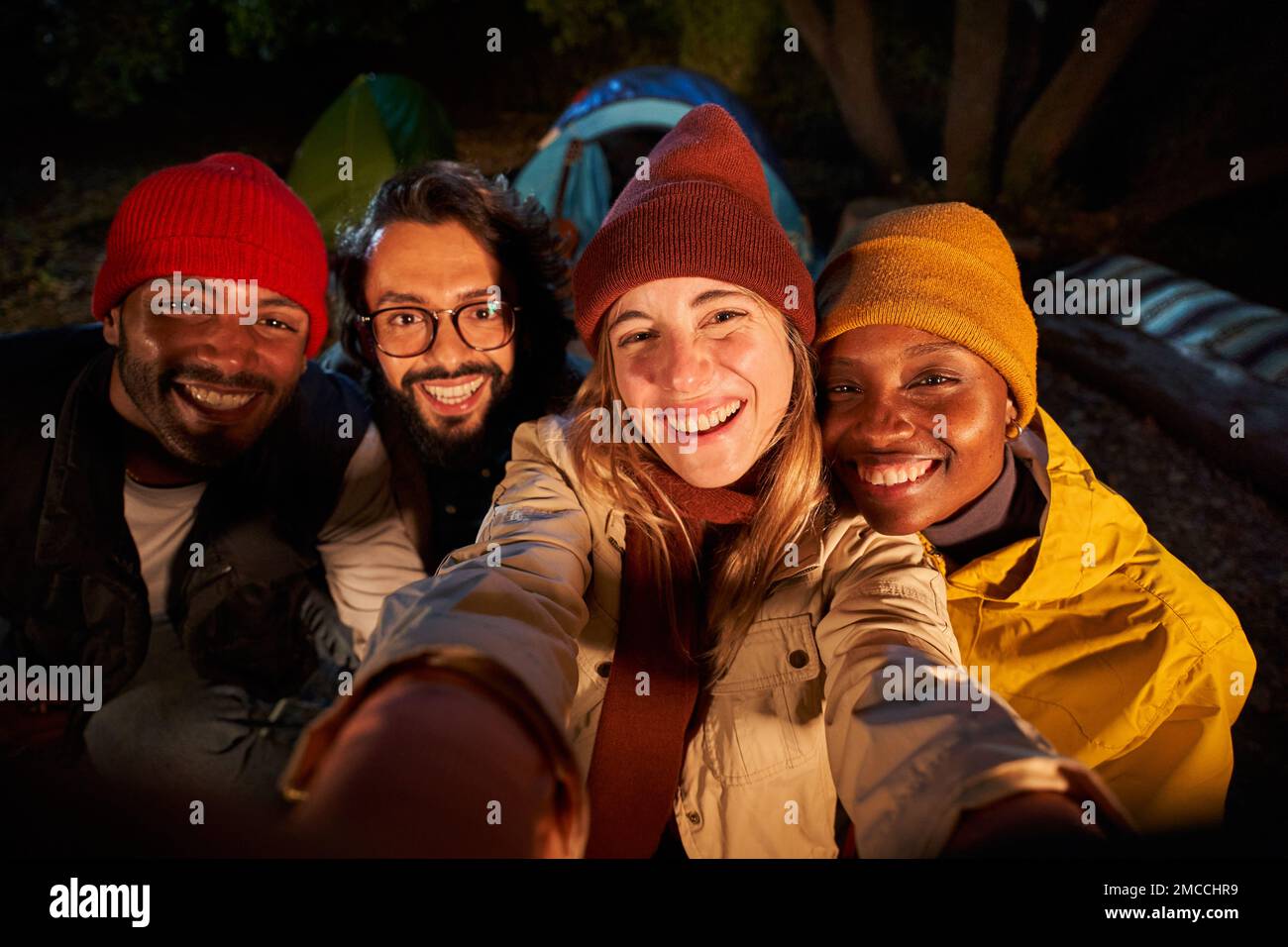 Photo of men and women smiling and taking selfie in camping forest. Stock Photo