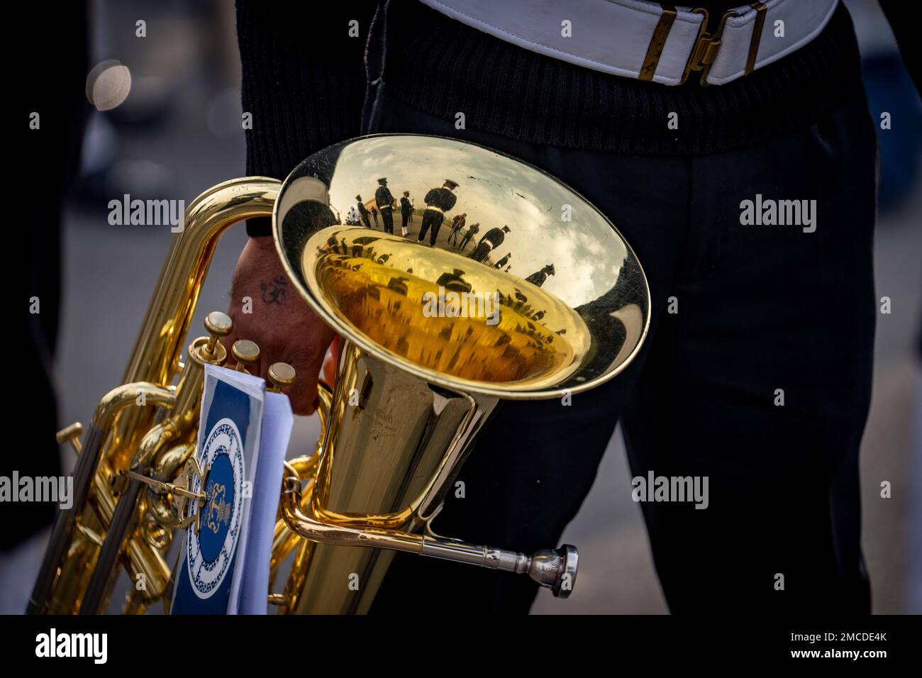 Members of an Indian Navy band are reflected on a brass instrument