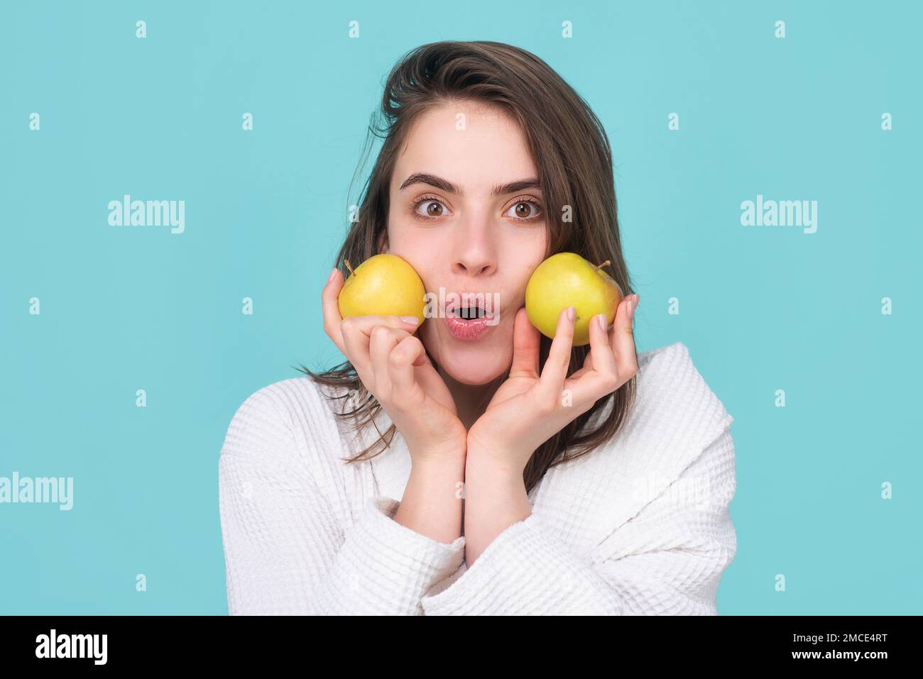 Surprised woman with apple near face. Healthcare and dental care