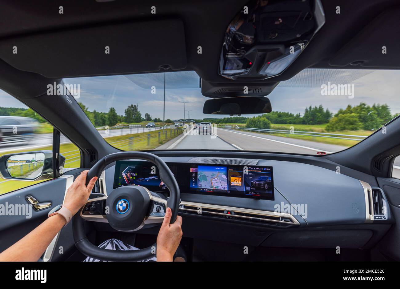 View of hands of woman driving new BMW iX40 electric car driving along ...