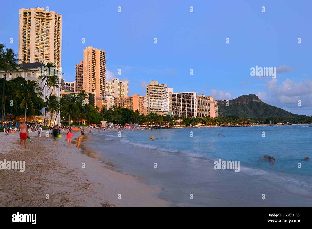 Dusk settles on the people and tides of Waikiki Beach, Diamond Head and the Pacific Ocean in Hawaii Stock Photo