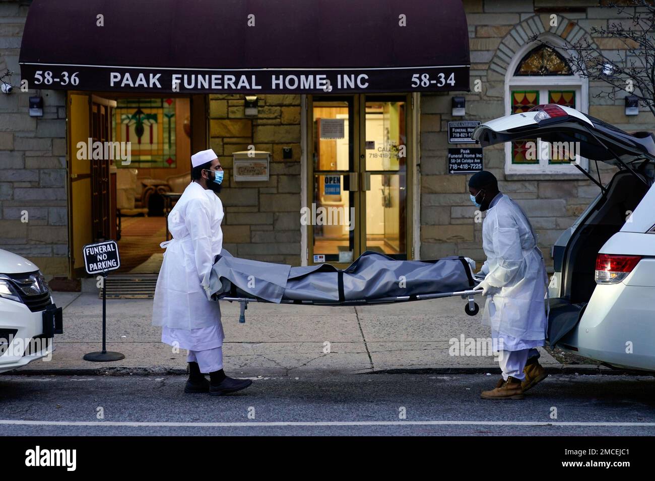 Men unload the bodies of victims of a building fire at a funeral home