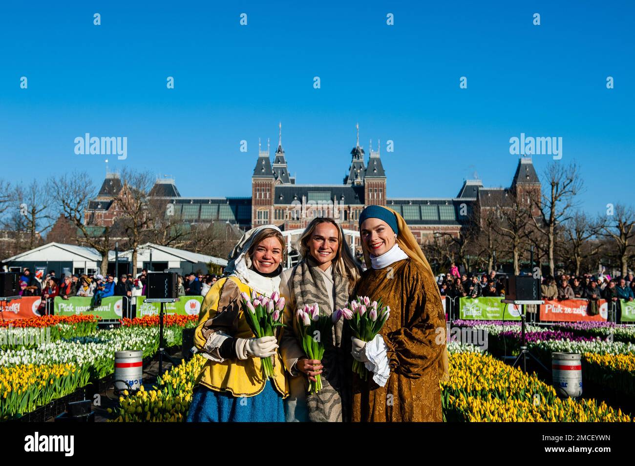 Olympic skating champion, Irene Schouten (middle) seen posing with two women dressing like two characters from the paintings of Johannes Vermeer. Each year on the 3rd Saturday of January, the National Tulip Day is celebrated in Amsterdam. Dutch tulip growers built a huge picking garden with more than 200,000 colorful tulips at the Museumplein in Amsterdam. Visitors are allowed to pick tulips for free. The event was opened by Olympic skating champion, Irene Schouten. Prior to the opening, she christened a new tulip: Tulipa 'Dutch Pearl' as a reference to the world - famous painting 'The girl wi Stock Photo