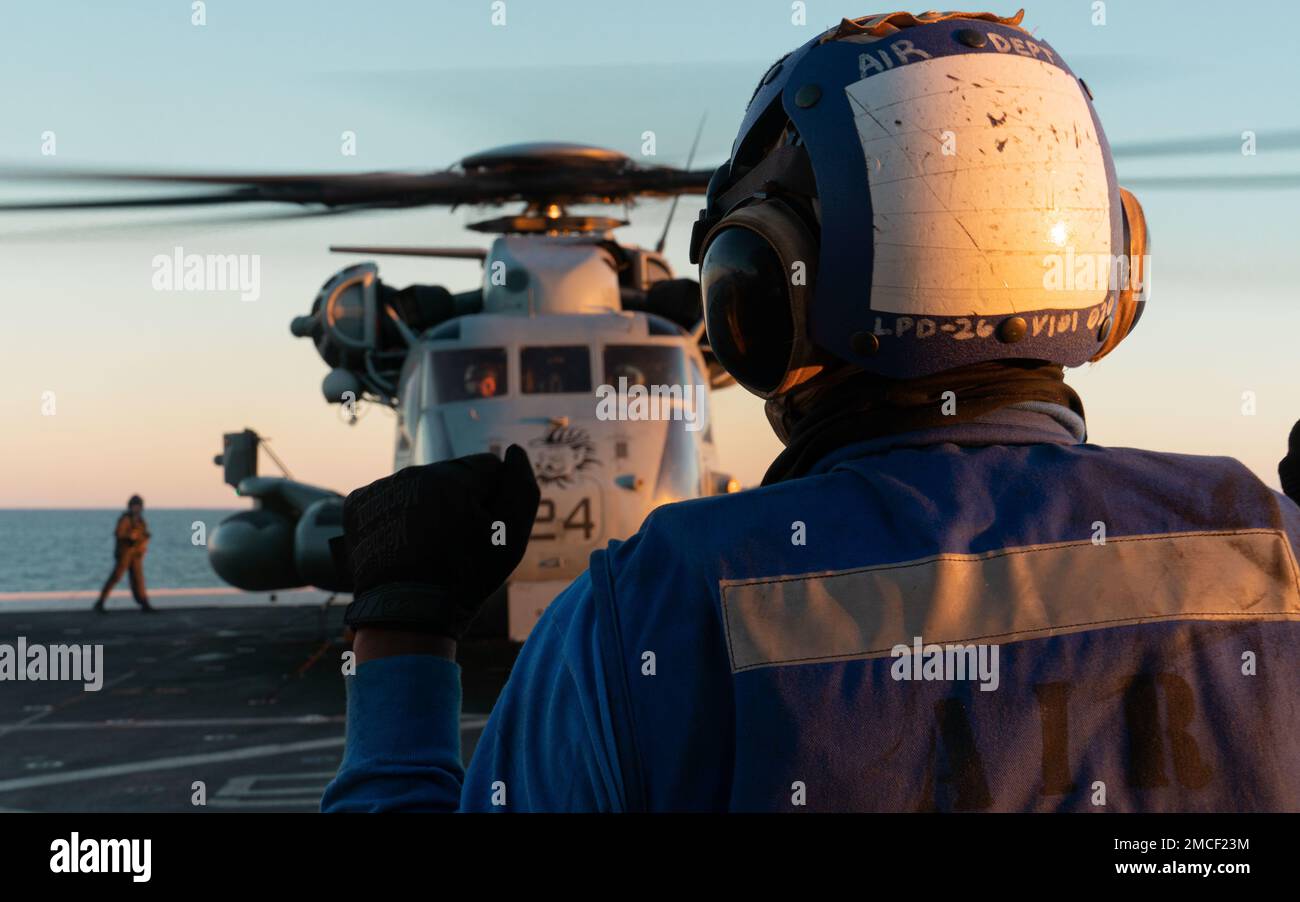 PACIFIC OCEAN (Nov. 11, 2022) – U.S. Navy Aviation Boatswains Mate Handler Airman Trion Hamilton with Air Department, USS John P. Murtha (LPD 26), signals U.S. Marine Corps Capt. Christopher Stebbins, a CH-53E Super Stallion aircraft commander and Capt. Mokoto Morita, a co-pilot, both with Marine Medium Tiltrotor Squadron (VMM) 362 (Rein.), 13th Marine Expeditionary Unit, during preflight operations, Nov. 11. The mobility and sustainability provided by amphibious platforms enable the Navy-Marine Corps team to extend the reach of our capabilities. The 13th Marine Expeditionary Unit is embarked Stock Photo