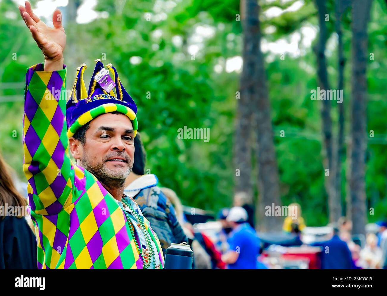 A man wearing a Mardi Gras costume waves during the Krewe de la