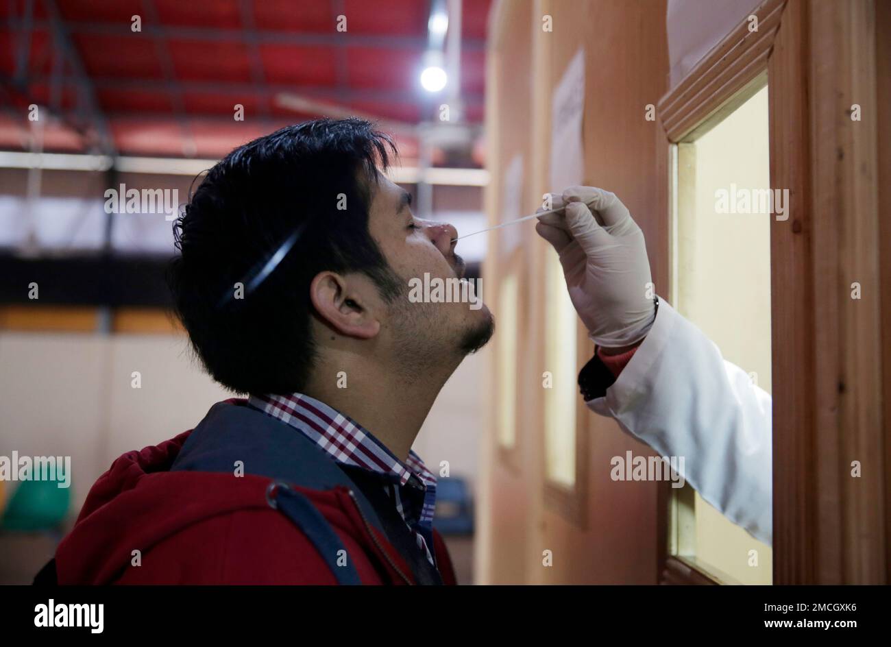A Pakistani lab technician takes a sample with a swab to test for the