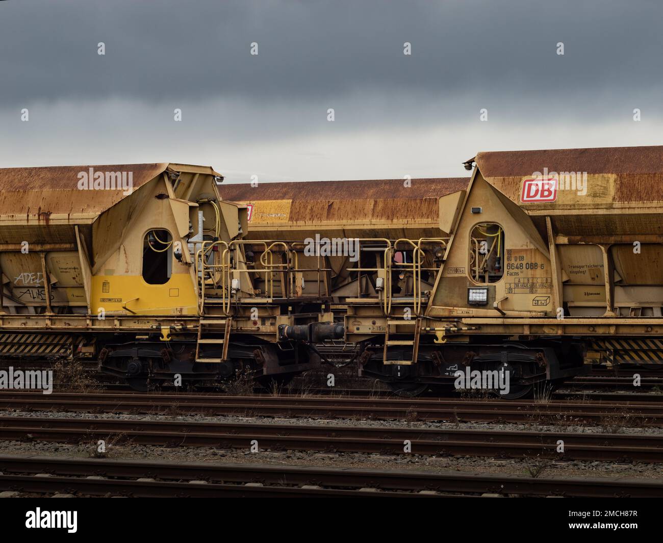 Facns 141 open freight wagons of the Deutsche Bahn company. Rusty steel on the rails in a dark environment. DB cargo ballast wagons as technology. Stock Photo