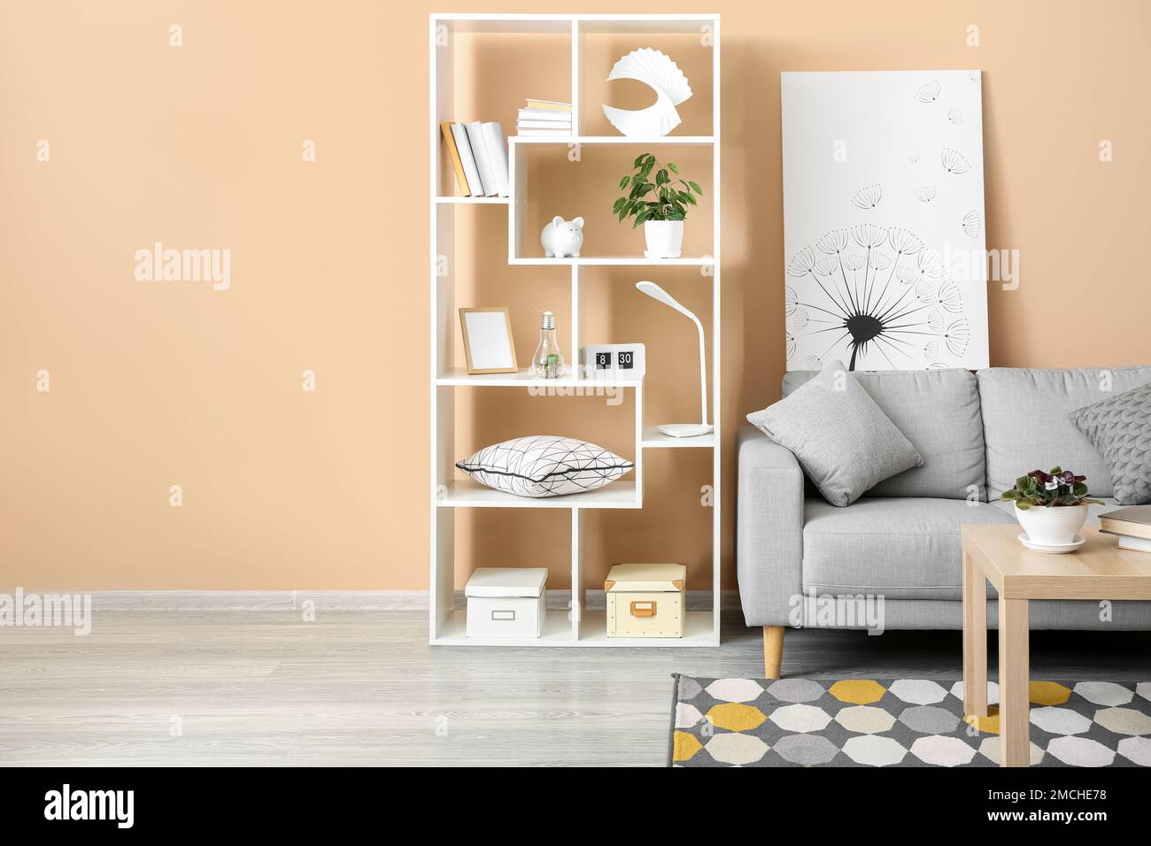 Interior of stylish living room with grey sofa, table and shelving unit ...
