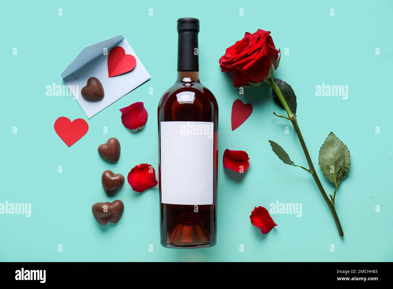 Bottle of wine, chocolate candies, rose flower and envelope on
