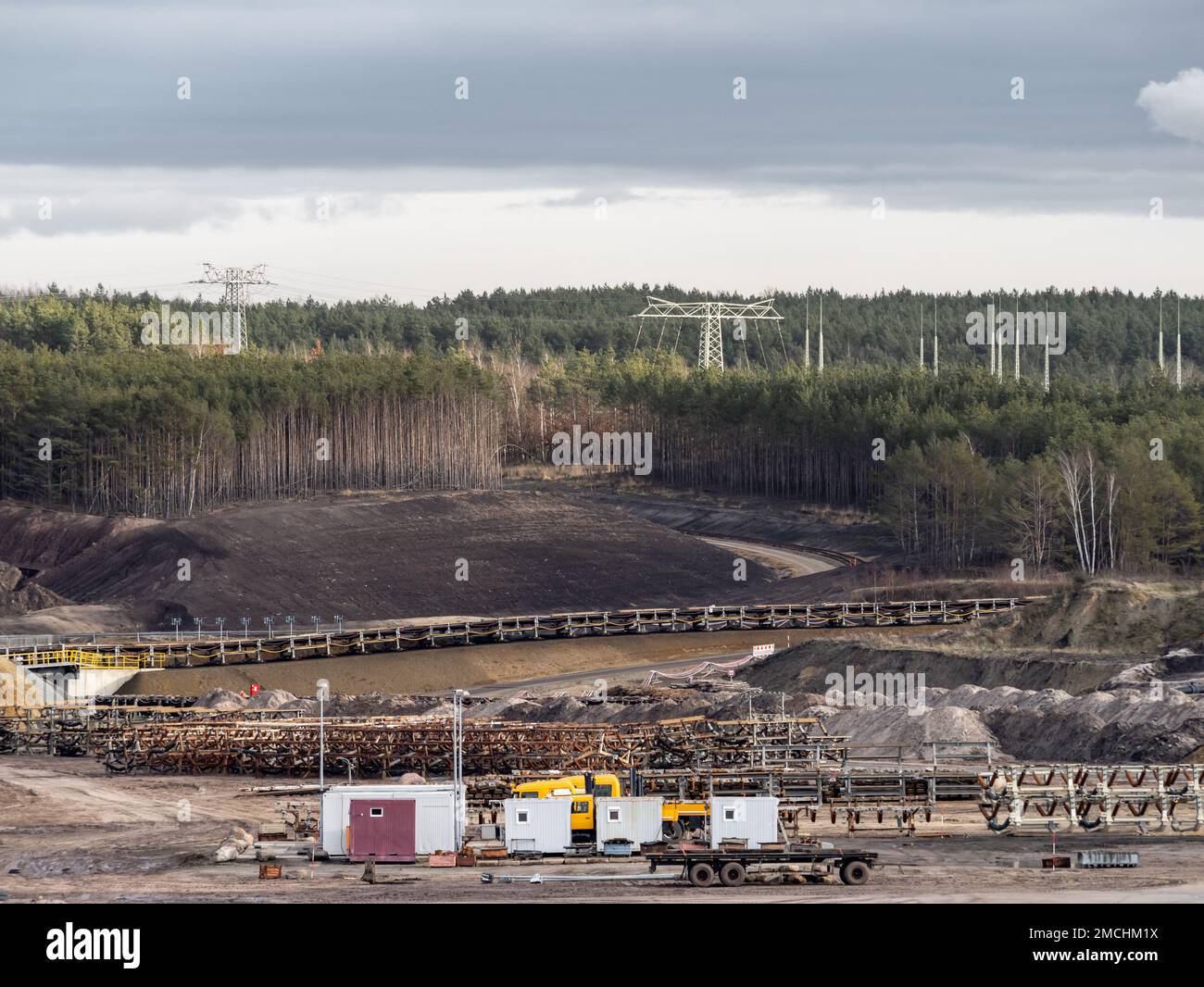 Conveyor belt parts lying in an open pit mine. Equipment for the transportation of lignite. The forest was destroyed for the exploitation. Stock Photo