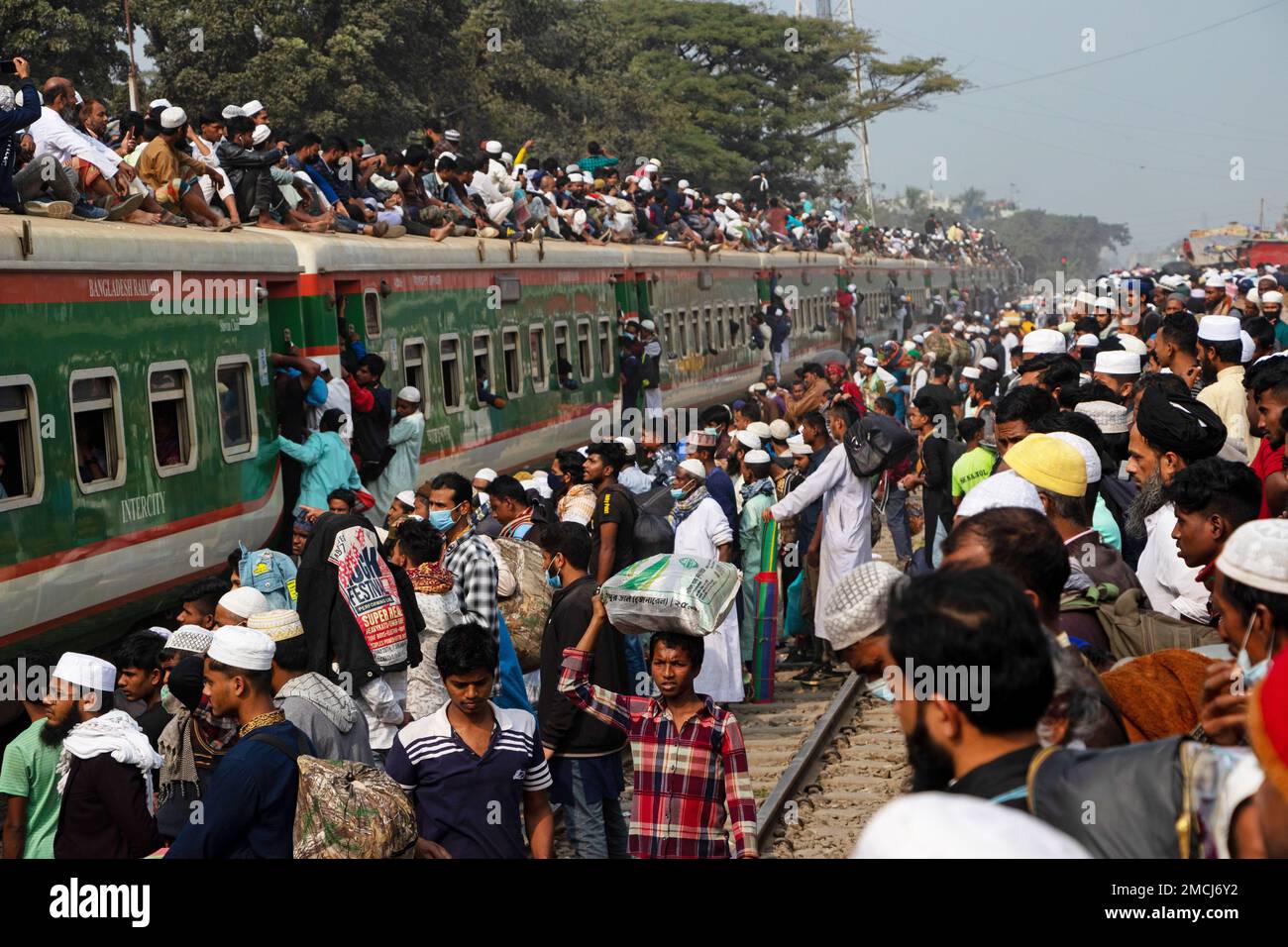 Dhaka, Bangladesh. 22nd Jan, 2023. Muslim devotees travel by overcrowded risky trains after attending the Akheri Munajat or final prayers, at the Biswa Ijtema in Tongi, Dhaka, Bangladesh. Locals tackle the journey climbing on, clinging to and clambering along the roofs of locomotives. With no seats available inside, many commuters decide to take the risk and choose a rooftop view for their journey out of Dhaka city. Credit: Joy Saha/Alamy Live News Stock Photo