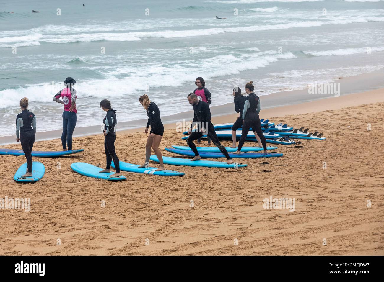 Beginners learning to surf on Manly beach, surf school teaches people of all ages how to use a