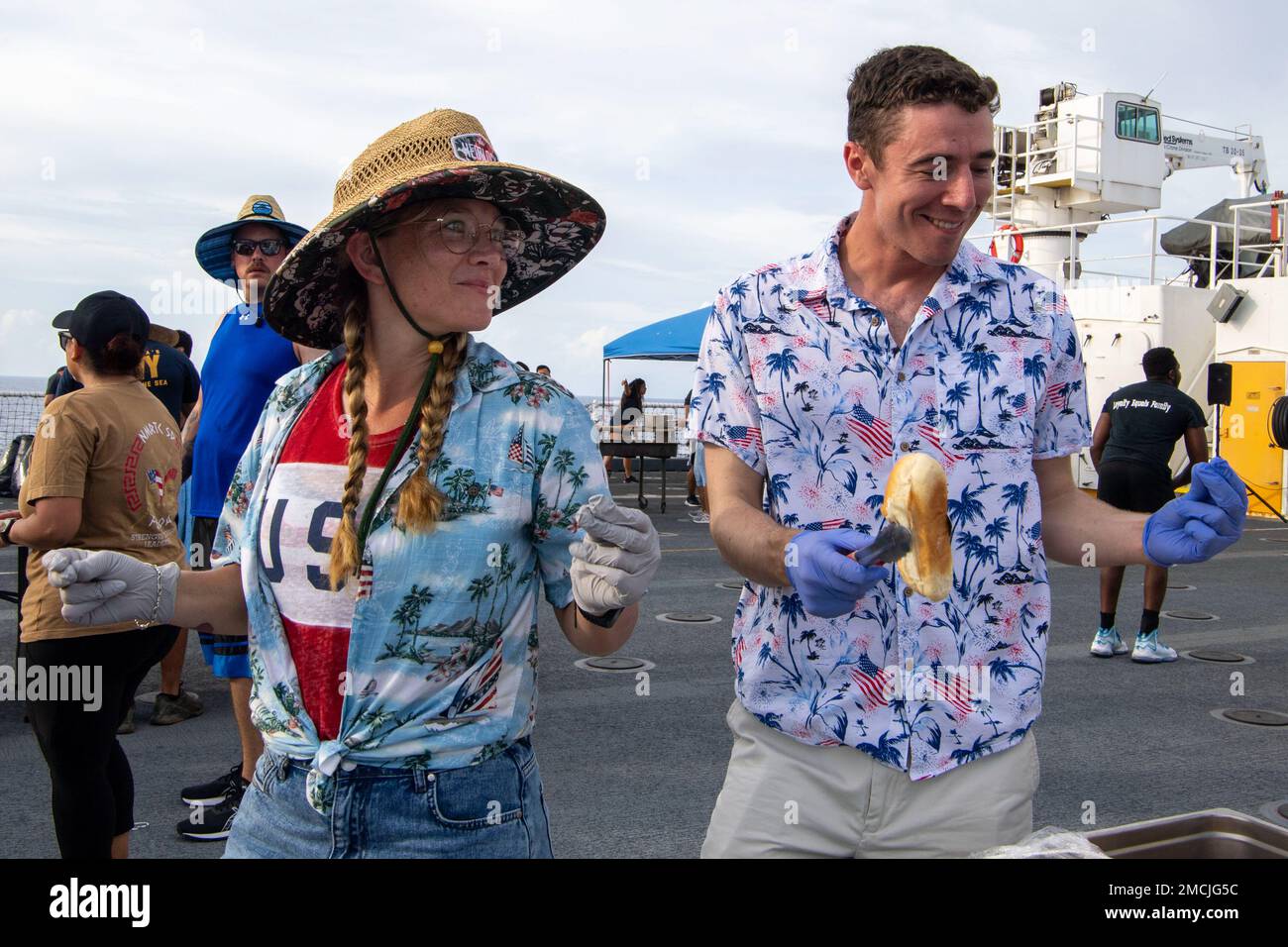 SOUTH CHINA SEA (July 5, 2022) – Lt. Bernadette Vingerhoets, from Hicksville, New York, left, and Lt. j.g. Charles Pitchford, from Norfolk, Virginia, dance and serve food during a Fourth of July celebration aboard Military Sealift Command hospital ship USNS Mercy (T-AH 19) while underway for Pacific Partnership 2022. Now in its 17th year, Pacific Partnership is the largest annual multinational humanitarian assistance and disaster relief preparedness mission conducted in the Indo-Pacific. Stock Photo