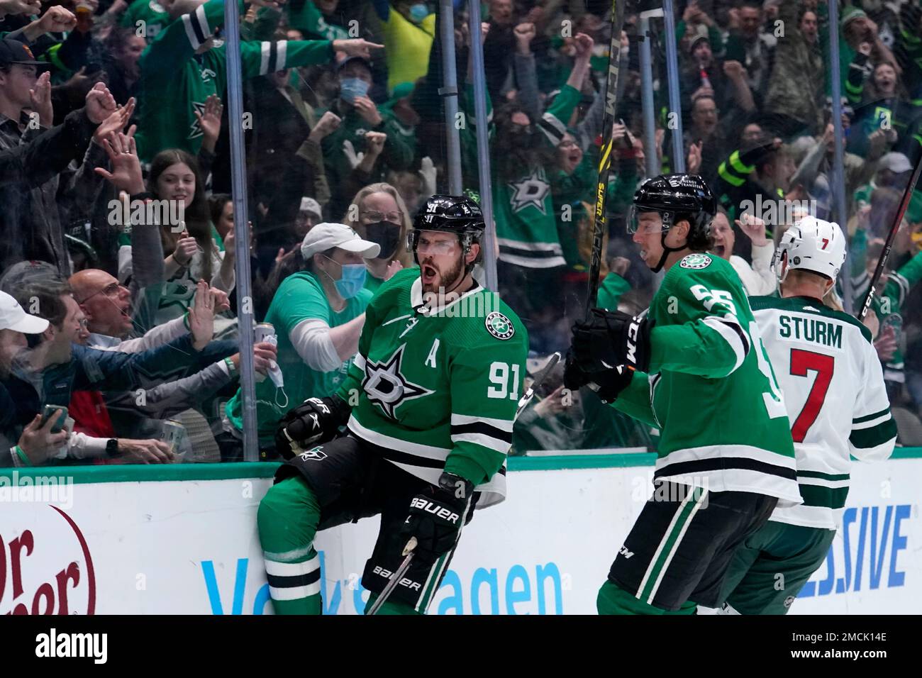 Fans cheer as Dallas Stars' Tyler Seguin (91) and Thomas (55) celebrate a goal scored by Seguin as Minnesota Wild center Nico Sturm (7) skates past in the first period of