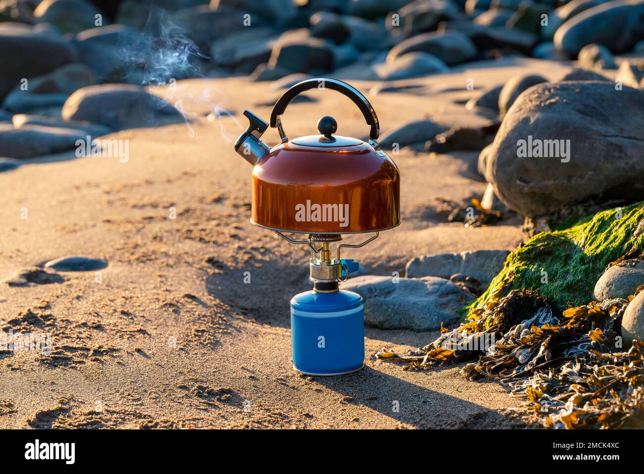 Portable tourist gas stove with a orange kettle on a background of