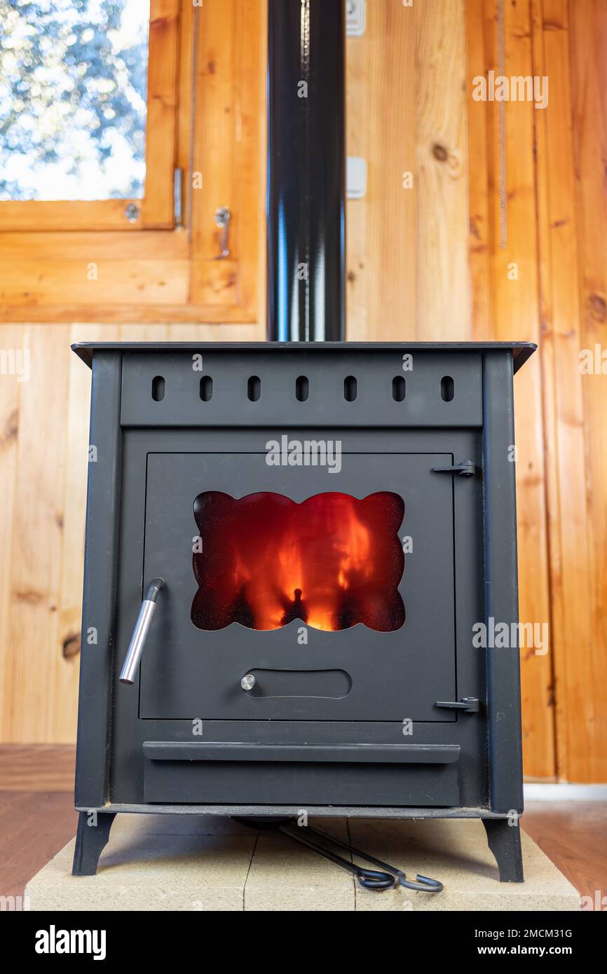Rustic cast iron stove with the fire lit inside to heat the house. Stock Photo