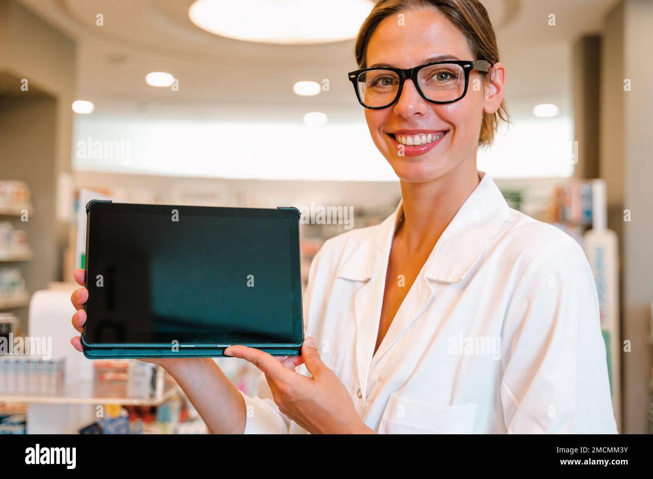 Woman pharmacist checks information on medicines on the tablet Stock Photo
