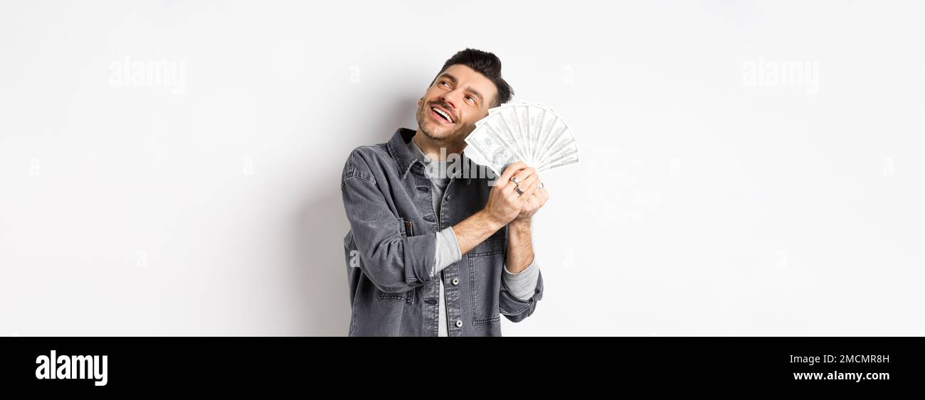 Happy rich guy hugging dollar bills and daydreaming, thinking of ...