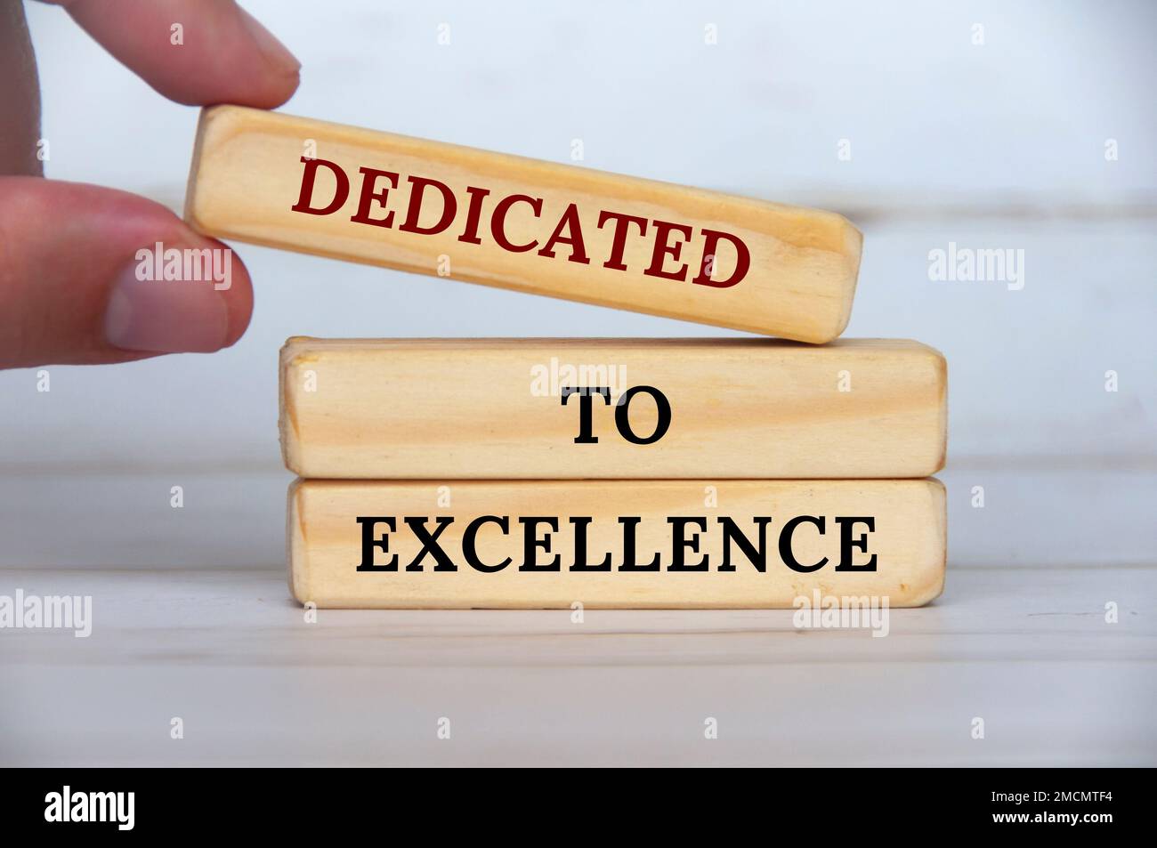 Dedicated to excellence text on wooden blocks with wooden cover background. Business motivation concept. Stock Photo