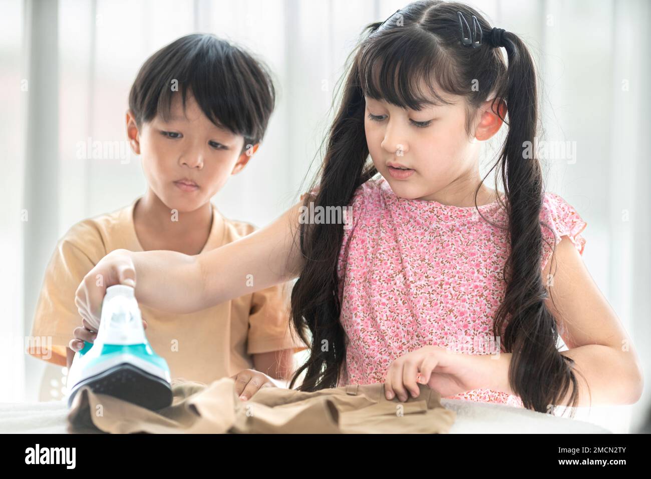 young happy boy and girl iron school uniform for education at home