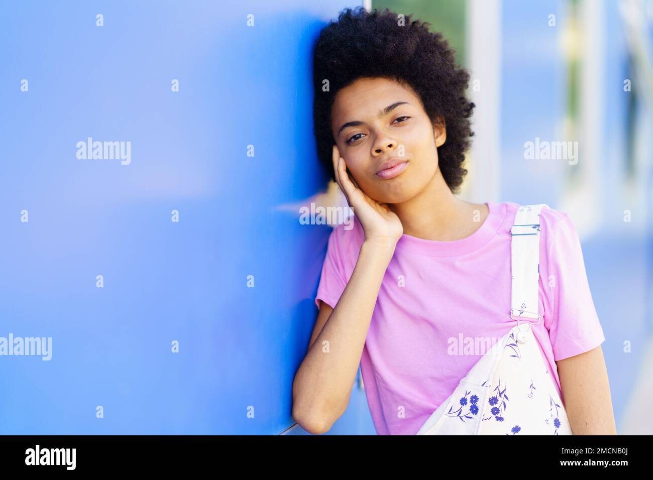 Charming black woman standing near house on street Stock Photo - Alamy