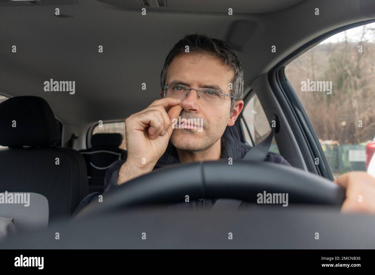 Man in car with finger into nose while driving. Stock Photo