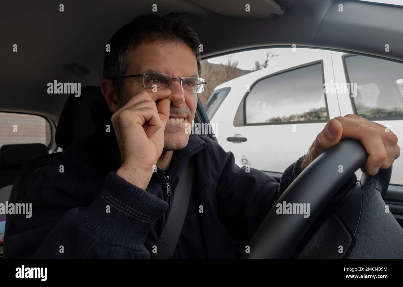 Man in car with finger into nose while driving Stock Photo