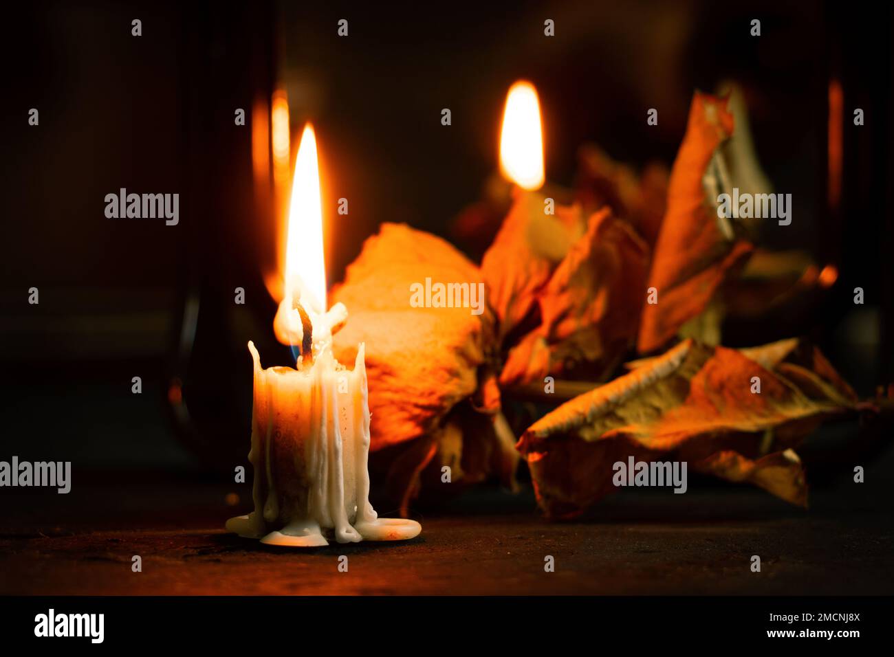burning candle near the mirror on the table and next to it lies a dry