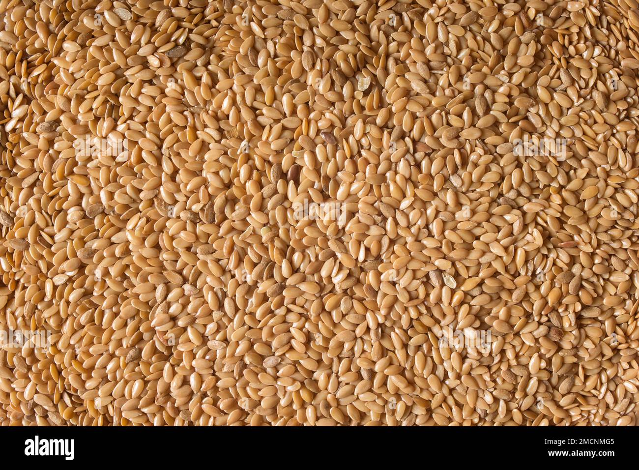 Top view of a close-up of a pile of cleaned golden flax seeds. Organic texture abstract background. Superfood. Stock Photo