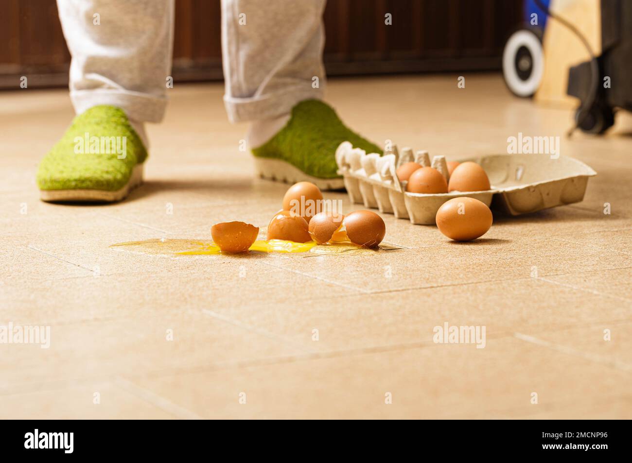 An unforeseen culinary mishap captured in a moment: eggs accidentally broken are scattered on the kitchen floor. The scene offers a glimpse into a mom Stock Photo