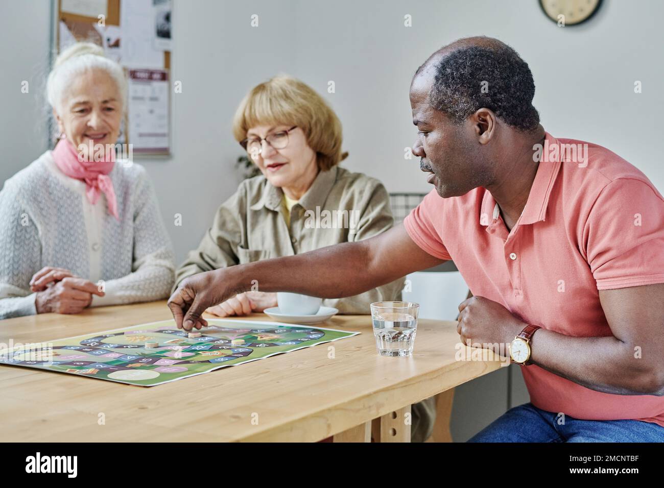 African American man playing board game with his friends at table during their leisure time Stock Photo
